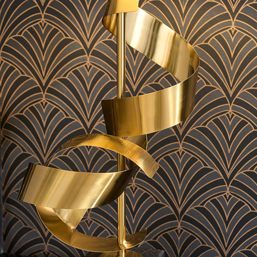 Close-up of the Clérachic gold spiral stem against dark art-deco wallpaper, showing the ribbon's brushed metal finish.