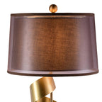 Close-up beneath the Clérachic lamp's brown drum shade, showing the gold spiral neck and finial ball at its base.