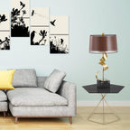 Clérachic gold spiral table lamp on a black hairpin-leg side table beside a grey sofa, with framed bird prints on a mint wall.
