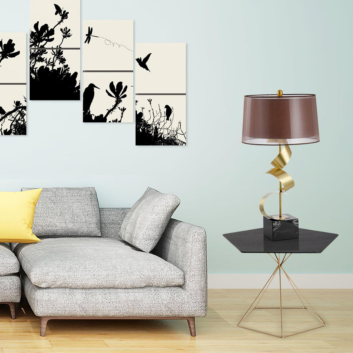 Clérachic gold spiral table lamp on a black hairpin-leg side table beside a grey sofa, with framed bird prints on a mint wall.
