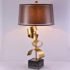 Clérachic table lamp with its plum-toned drum shade and gold spiral stem shown full-length on a plain lilac background.