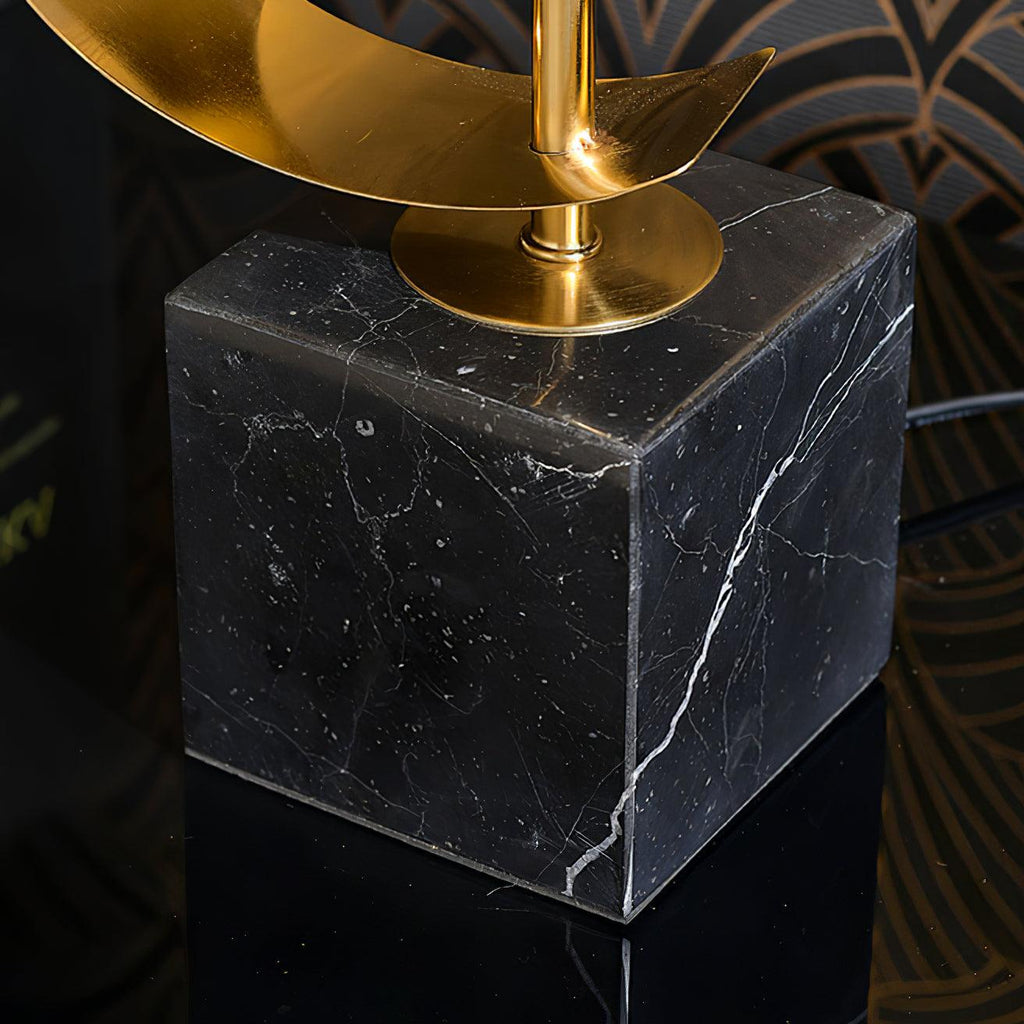 Close-up of the Clérachic gold spiral stem rising from its black marble base, cord trailing across a white surface.