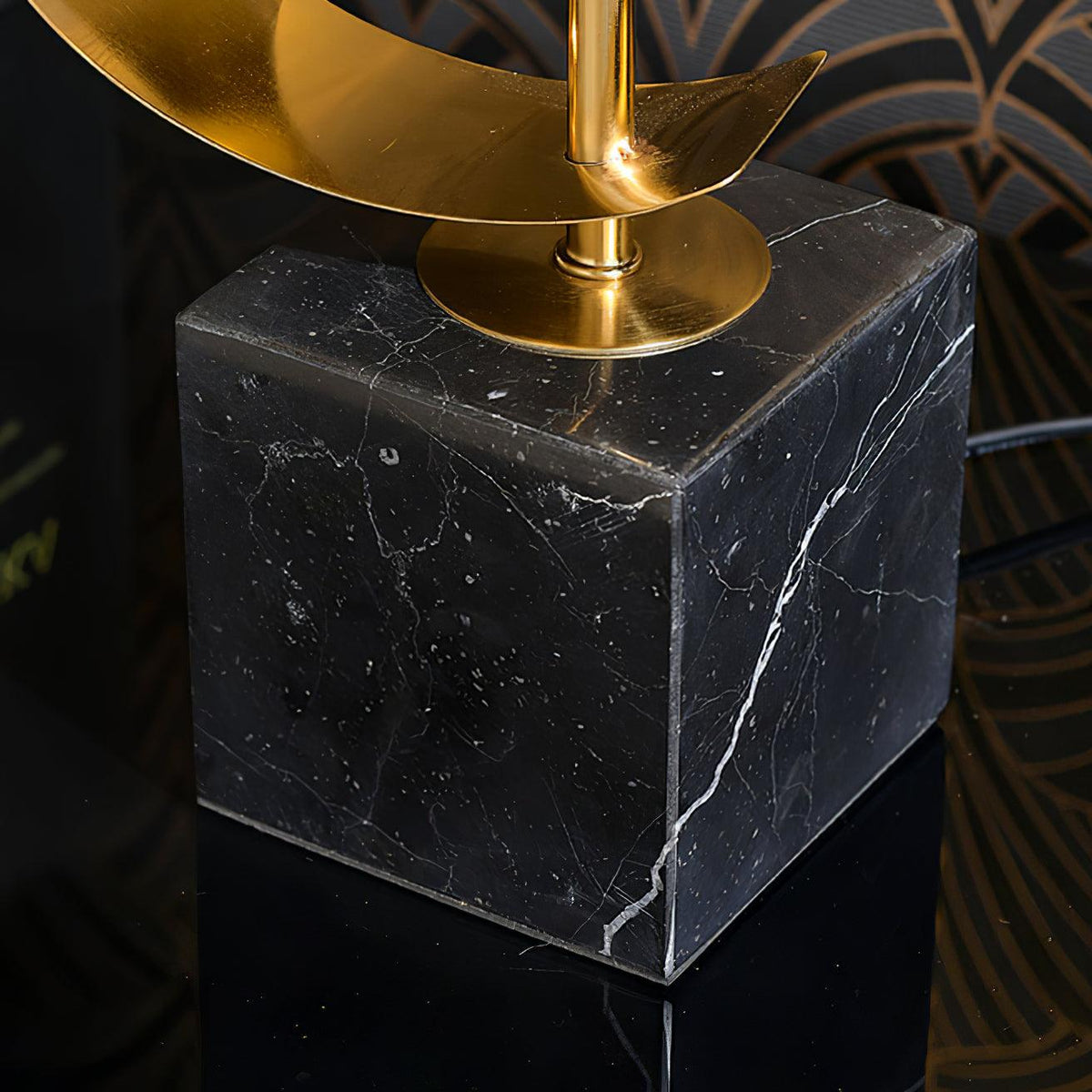 Close-up of the Clérachic gold spiral stem rising from its black marble base, cord trailing across a white surface.