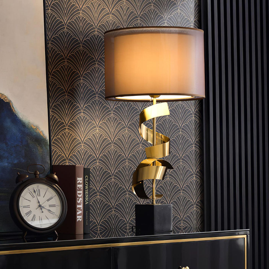 Clérachic gold spiral table lamp on a black lacquered credenza with gilt trim, set against dark art-deco wallpaper.