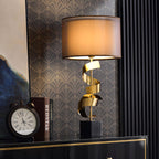 Clérachic gold spiral table lamp on a black lacquered credenza with gilt trim, set against dark art-deco wallpaper.