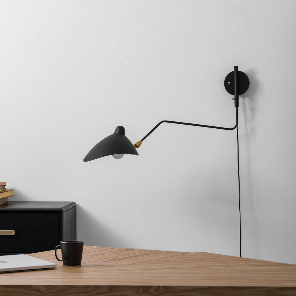 Wall sconce arm extended at full reach over a chair