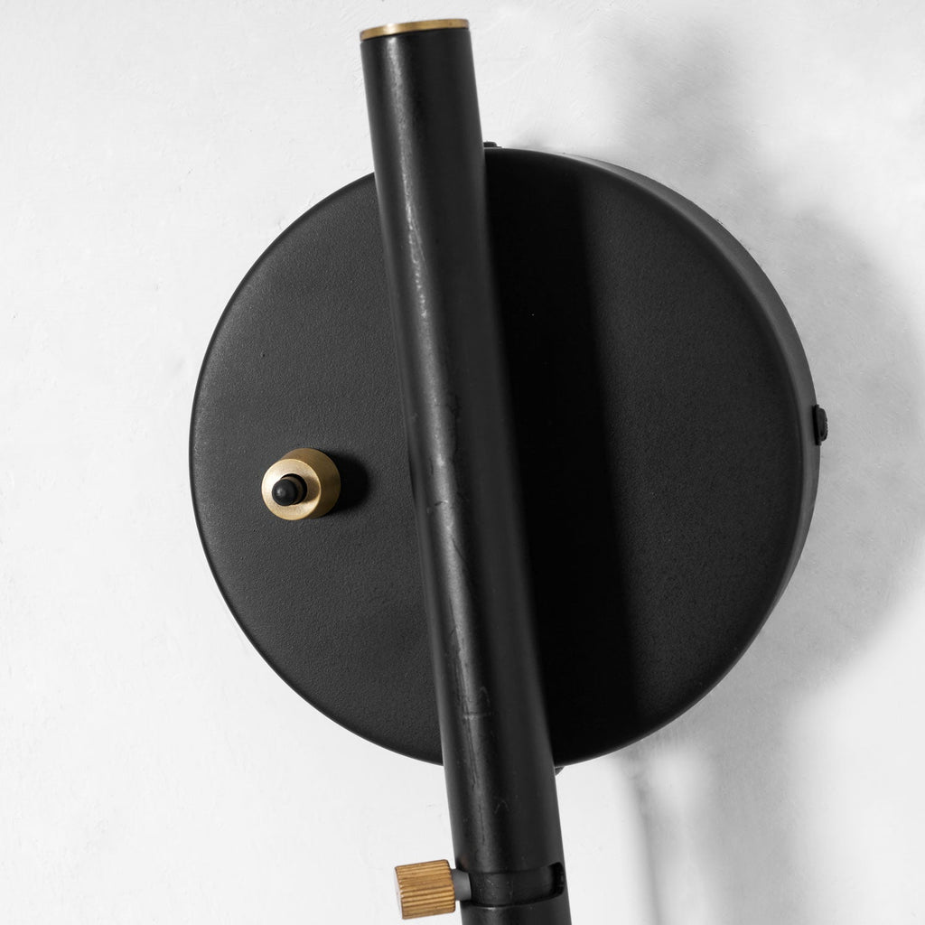 Swing-arm wall sconce shown against a dark feature wall