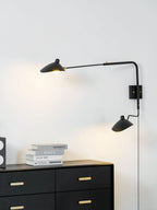 Single-arm wall sconce shown beside a bed for reading light