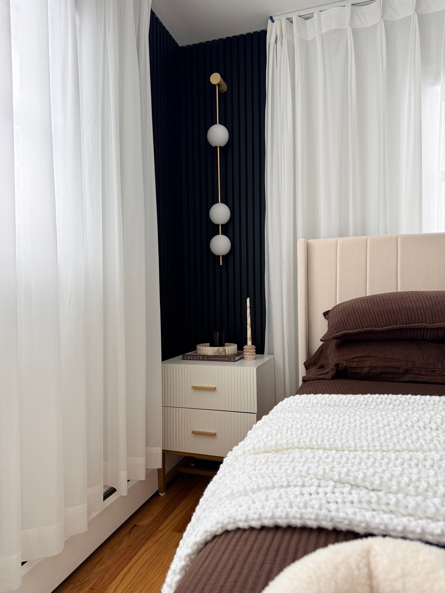 Wall lamp with stacked globe shades shown against a neutral wall