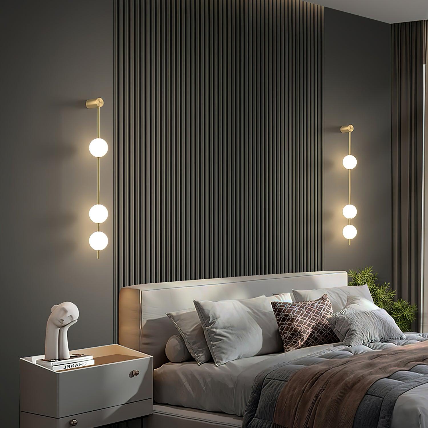 Brass vertical wall lamp with glowing globes shown in detail