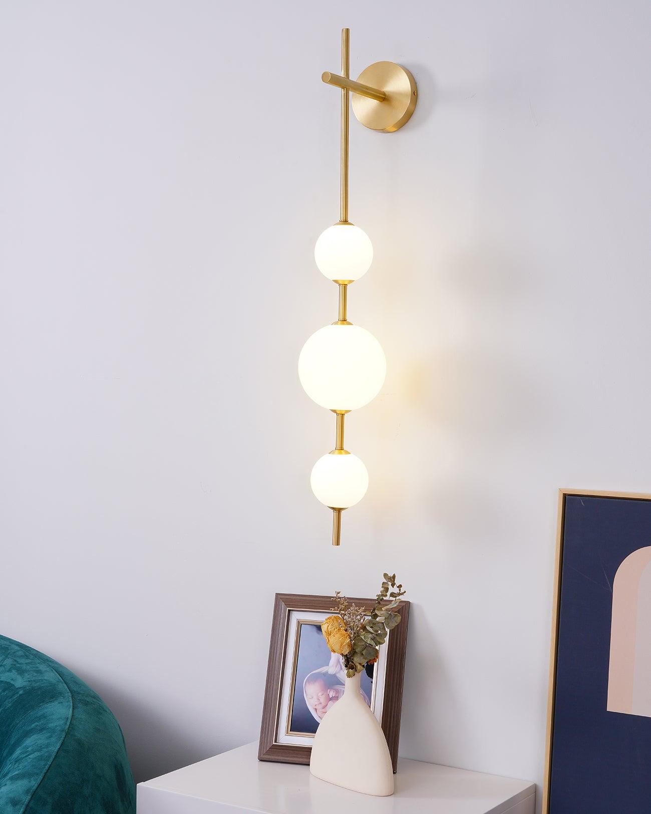 Stacked glass globe wall lamp glowing warmly in a living space