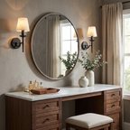 In matte black, a pair of Clérachic sconces flanks a round mirror above a vanity set with a tray and vase.
