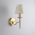 Seen in brushed brass against white, this Clérachic sconce tapers from a round wall plate to its alabaster shade.