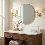 Against a shiplap wall, a brass pair of these Clérachic sconces lights a round mirror above a vanity.