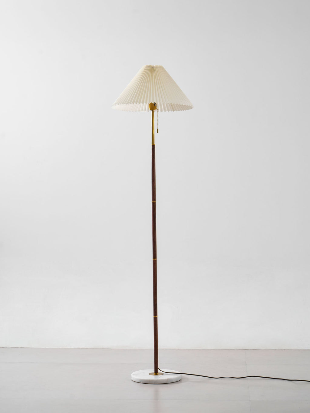 Clérachic pleated fabric shade floor lamp on white background, its shade lit to show the fabric's folds.