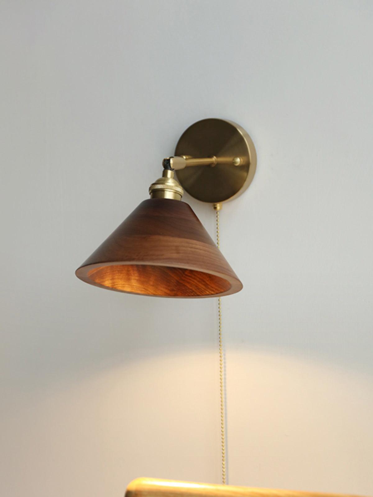 Brass and walnut wall sconce lighting a hallway corner