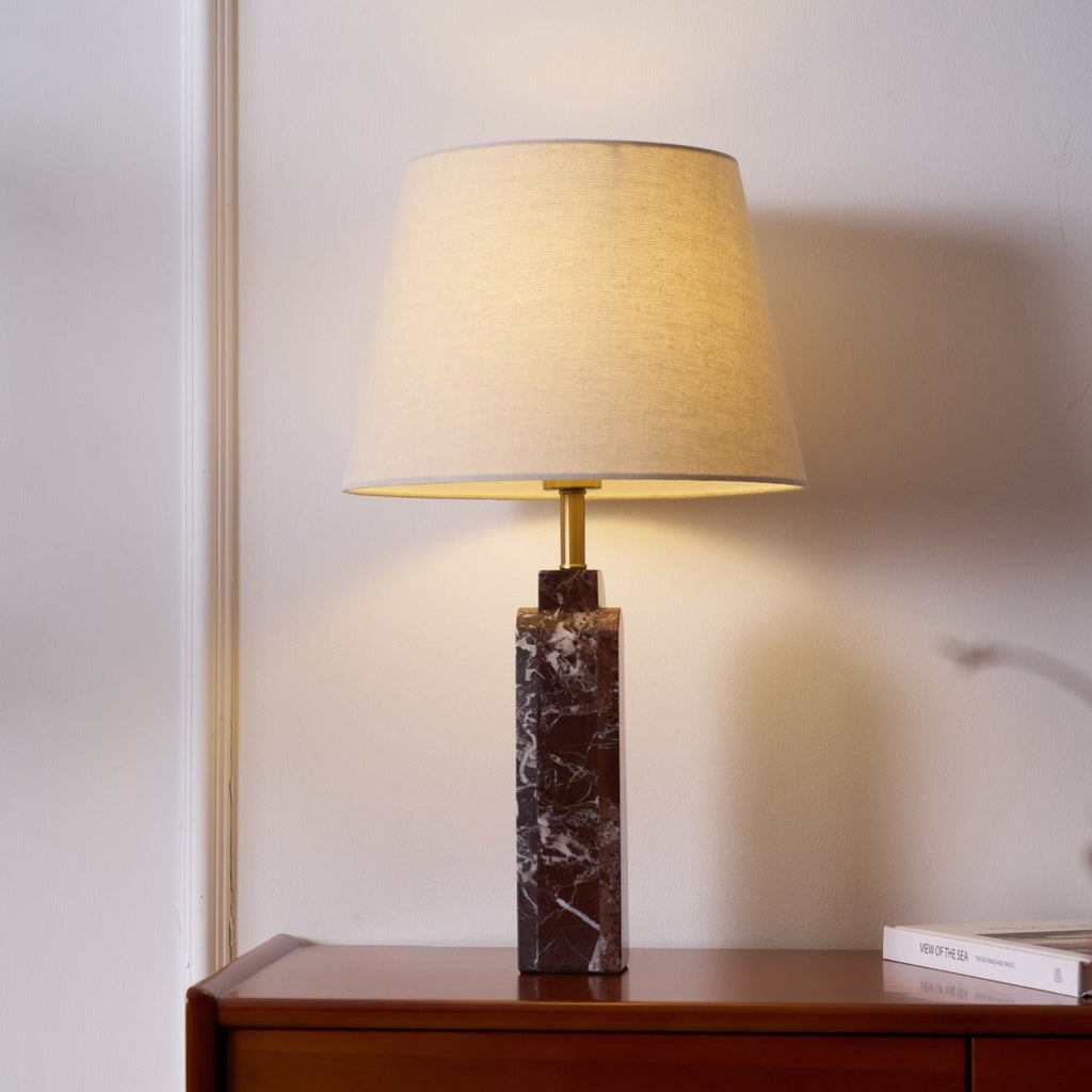A Clérachic marble table lamp glows on a bedside dresser, a book resting at its base beside the shade's light.