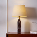 A Clérachic marble table lamp glows on a bedside dresser, a book resting at its base beside the shade's light.