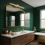 A round mirror in a green subway-tiled bathroom sits beneath this Clérachic wall light in brass, above a walnut vanity.