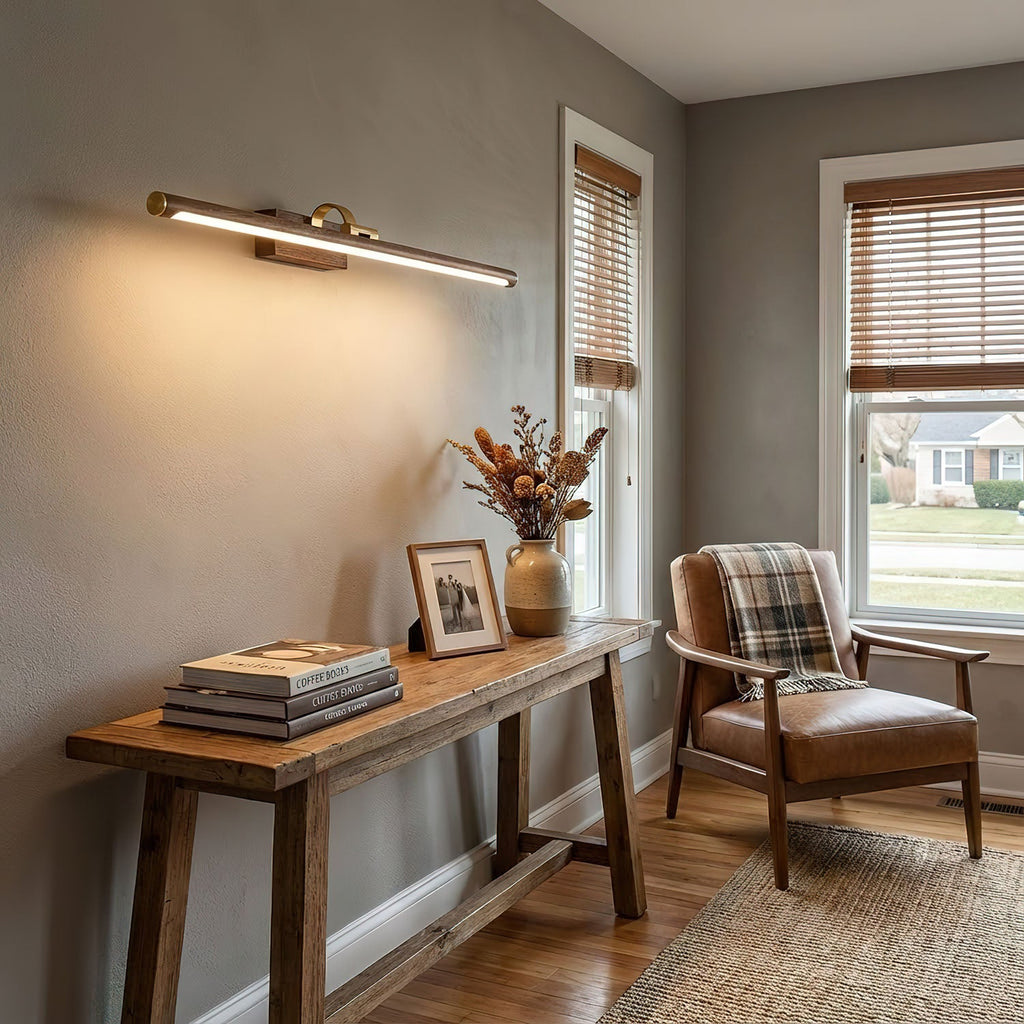 In a pale grey hallway, this Clérachic wall light in brass sits above a wooden console table and armchair.