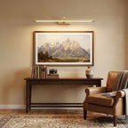 Mounted over a mountain print, this Clérachic wall light in brass lights a dark wood console table with books.