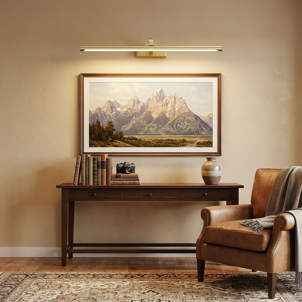Mounted over a mountain print, this Clérachic wall light in brass lights a dark wood console table with books.