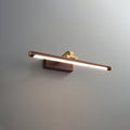This Clérachic wall light in walnut and brass, lit, shown at a three-quarter angle on plain grey.