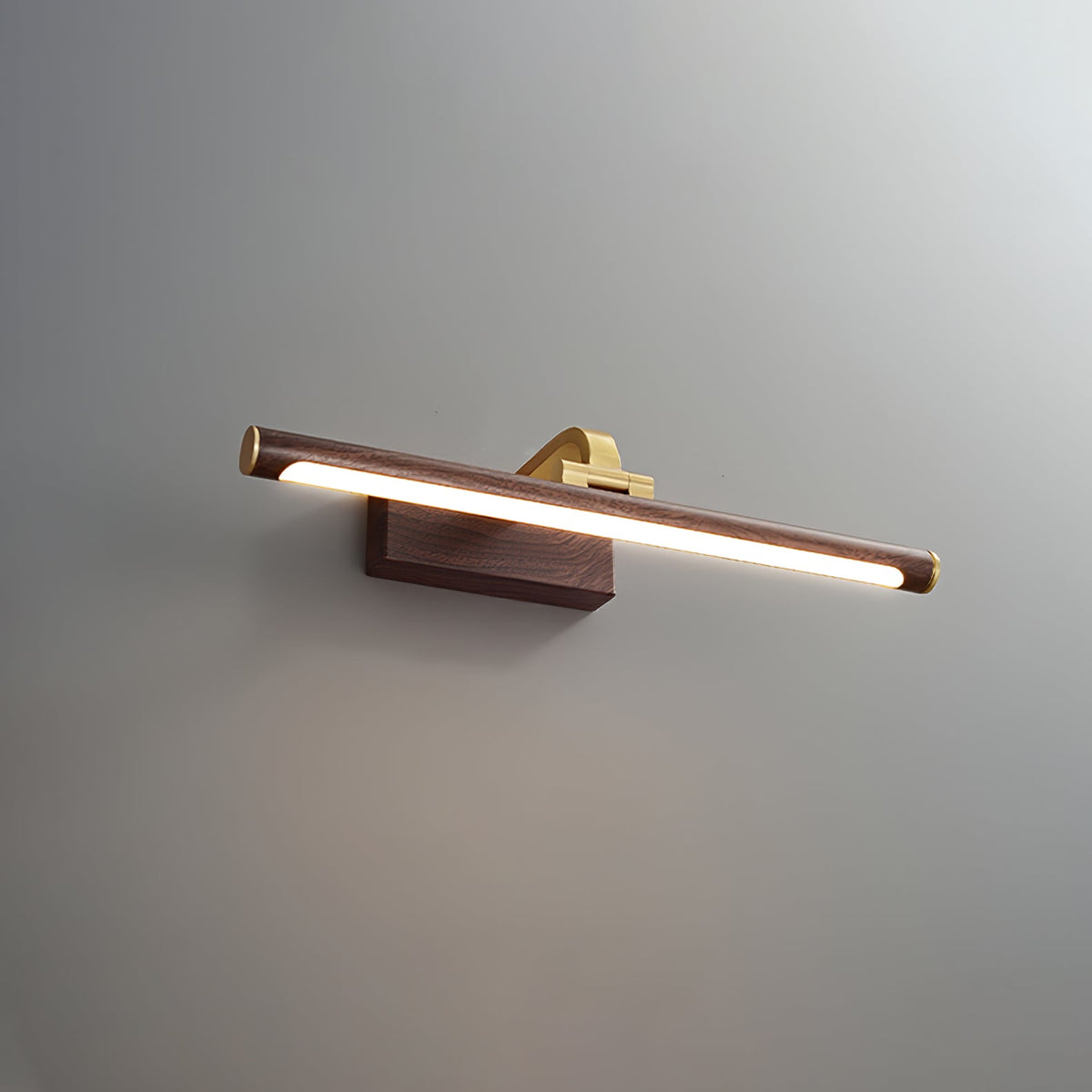 This Clérachic wall light in walnut and brass, lit, shown at a three-quarter angle on plain grey.