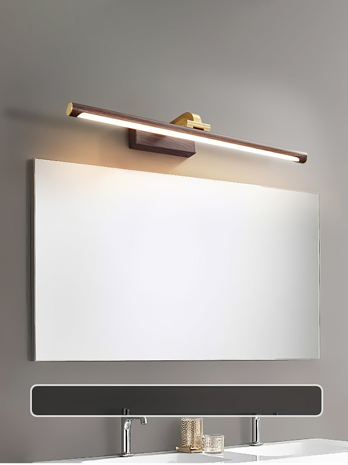 A wide mirror over a bathroom counter sits beneath this Clérachic wall light in walnut and brass, lit.