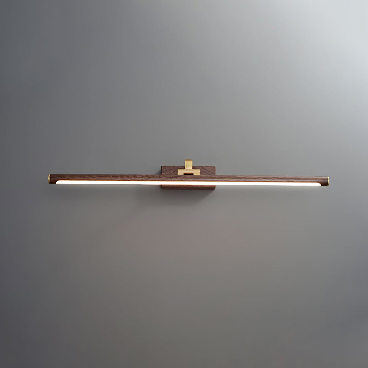 Straight-on view of this Clérachic wall light in walnut and brass, lit, on plain grey.