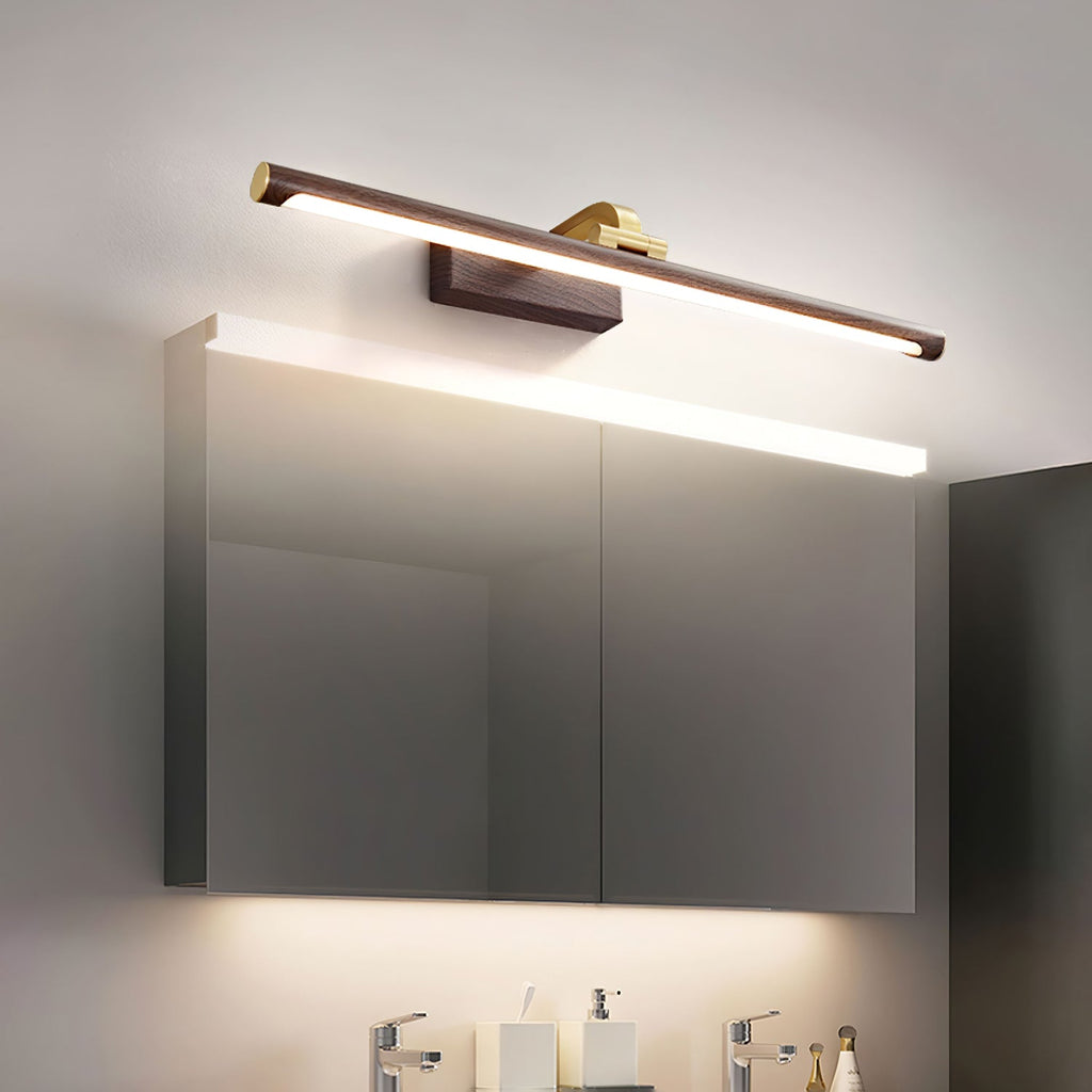 Above a mirrored bathroom cabinet, this Clérachic wall light in walnut and brass casts warm light over the vanity below.