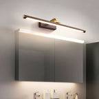 Above a mirrored bathroom cabinet, this Clérachic wall light in walnut and brass casts warm light over the vanity below.