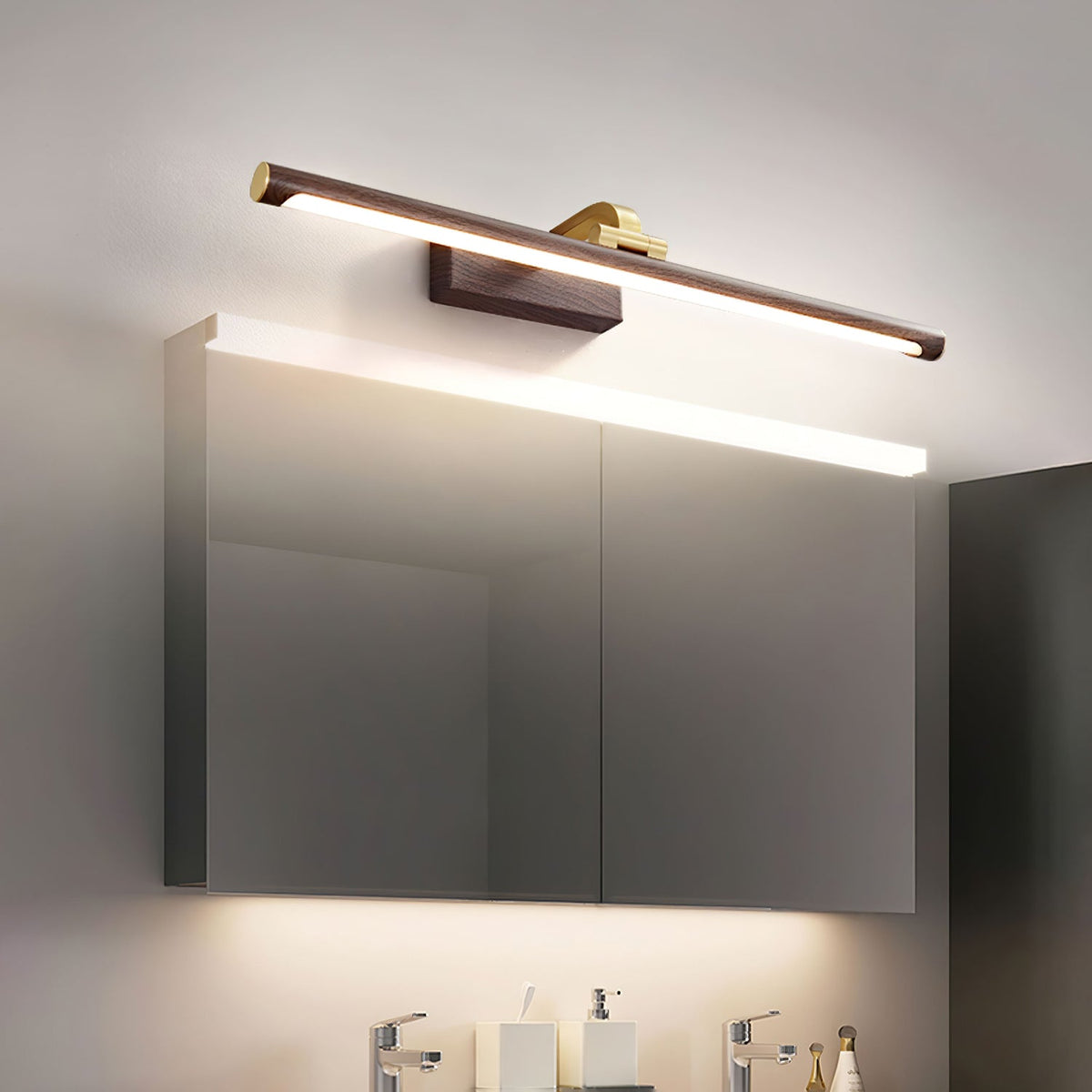 Above a mirrored bathroom cabinet, this Clérachic wall light in walnut and brass casts warm light over the vanity below.