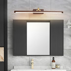 Mirrored cabinet doors sit below this Clérachic wall light in walnut and brass, over a dark wood vanity.