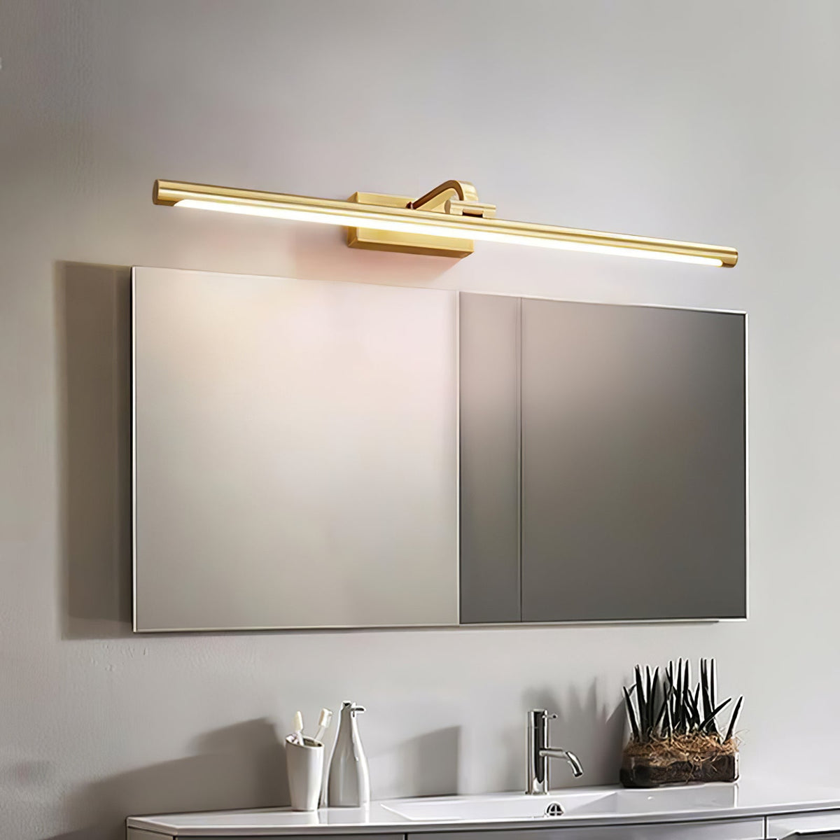 Small potted succulents sit on a white vanity beneath this Clérachic wall light in brass, above a mirrored cabinet.