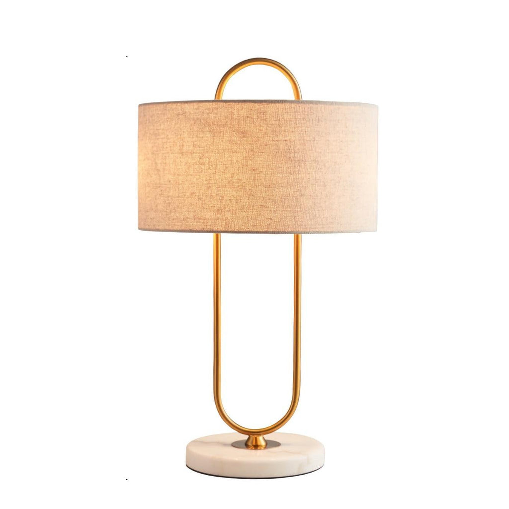 Standing alone on a white background, this Clérachic table lamp glows warm gold through its white linen drum shade.