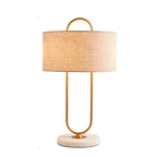 Standing alone on a white background, this Clérachic table lamp glows warm gold through its white linen drum shade.