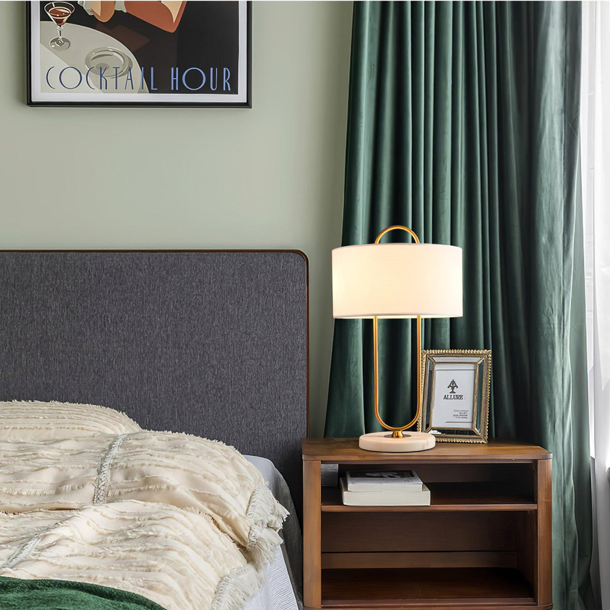 Against green curtains and a grey headboard, this Clérachic lamp sits on a wood nightstand beside a small framed photograph.