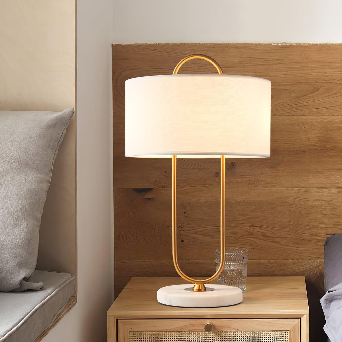 Warmly lit beside a glass of water, this Clérachic table lamp sits on a wood nightstand built into a panelled headboard nook.