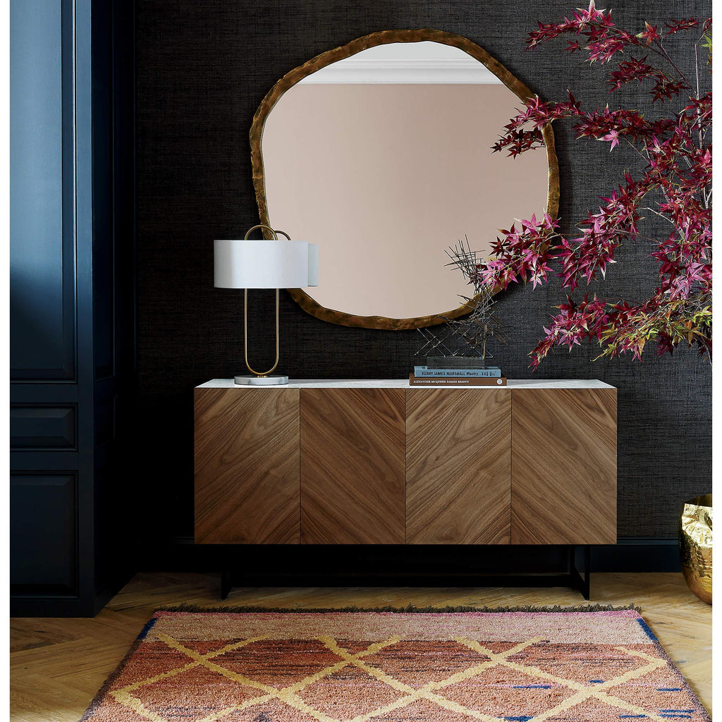 Placed on a wood sideboard beneath a round mirror, this Clérachic table lamp adds a small point of light to a dark teal room.