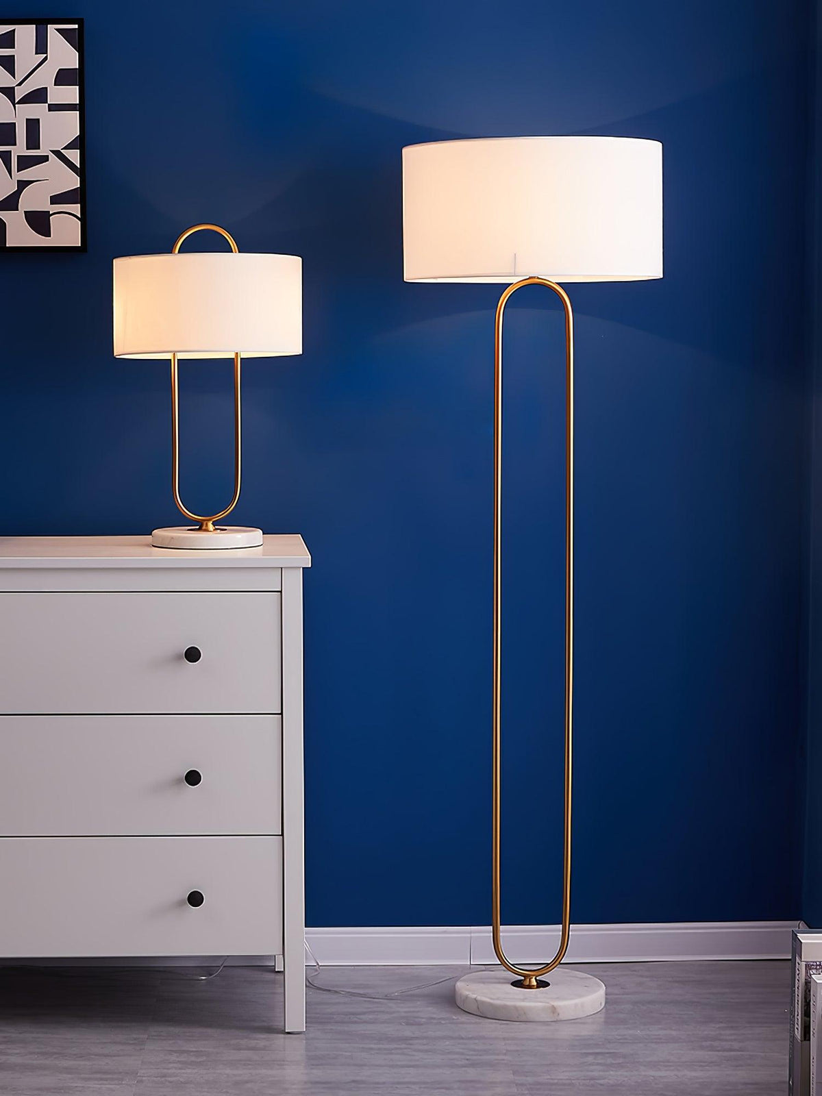 Shown beside its taller floor-lamp counterpart against a navy blue wall, this Clérachic table lamp sits on a white dresser.