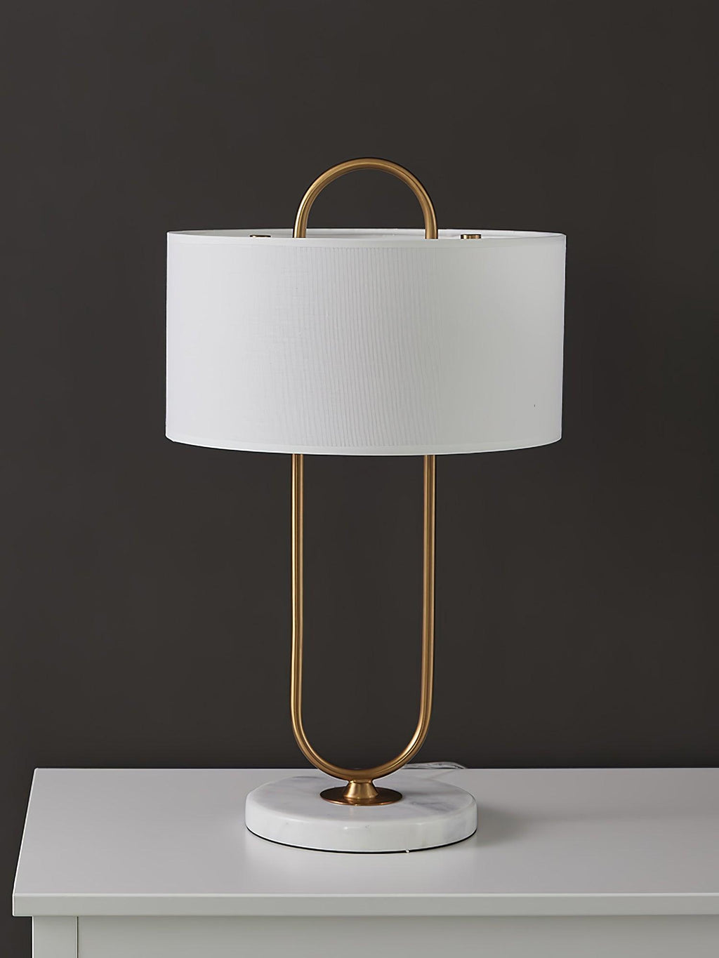 Photographed on a white dresser top against a dark charcoal backdrop, this Clérachic table lamp's marble base and brass frame stand out.