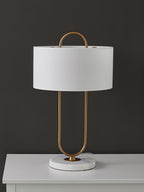 Photographed on a white dresser top against a dark charcoal backdrop, this Clérachic table lamp's marble base and brass frame stand out.