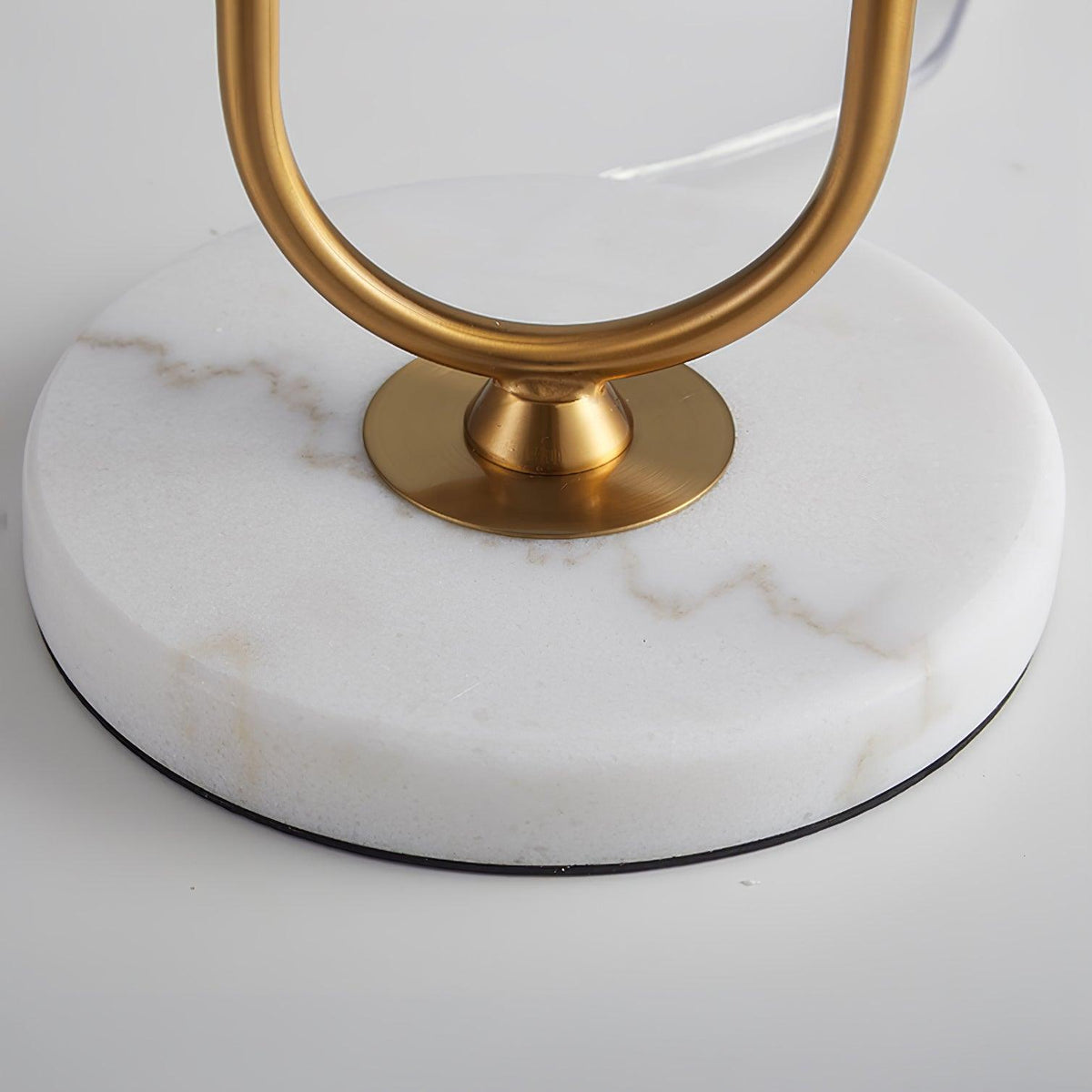 This close-up detail shows the veined marble base of a Clérachic table lamp where it meets the polished brass joint.