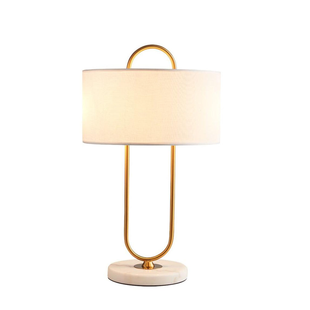 Cropped close against a plain white background, this lit Clérachic table lamp highlights the drum shade and looped brass frame.