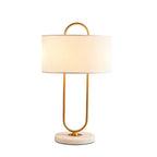 Cropped close against a plain white background, this lit Clérachic table lamp highlights the drum shade and looped brass frame.