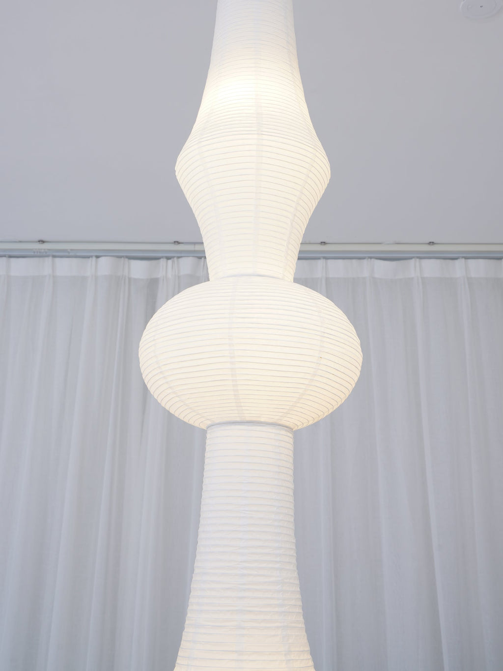 Slender white paper pendant shade shown from below