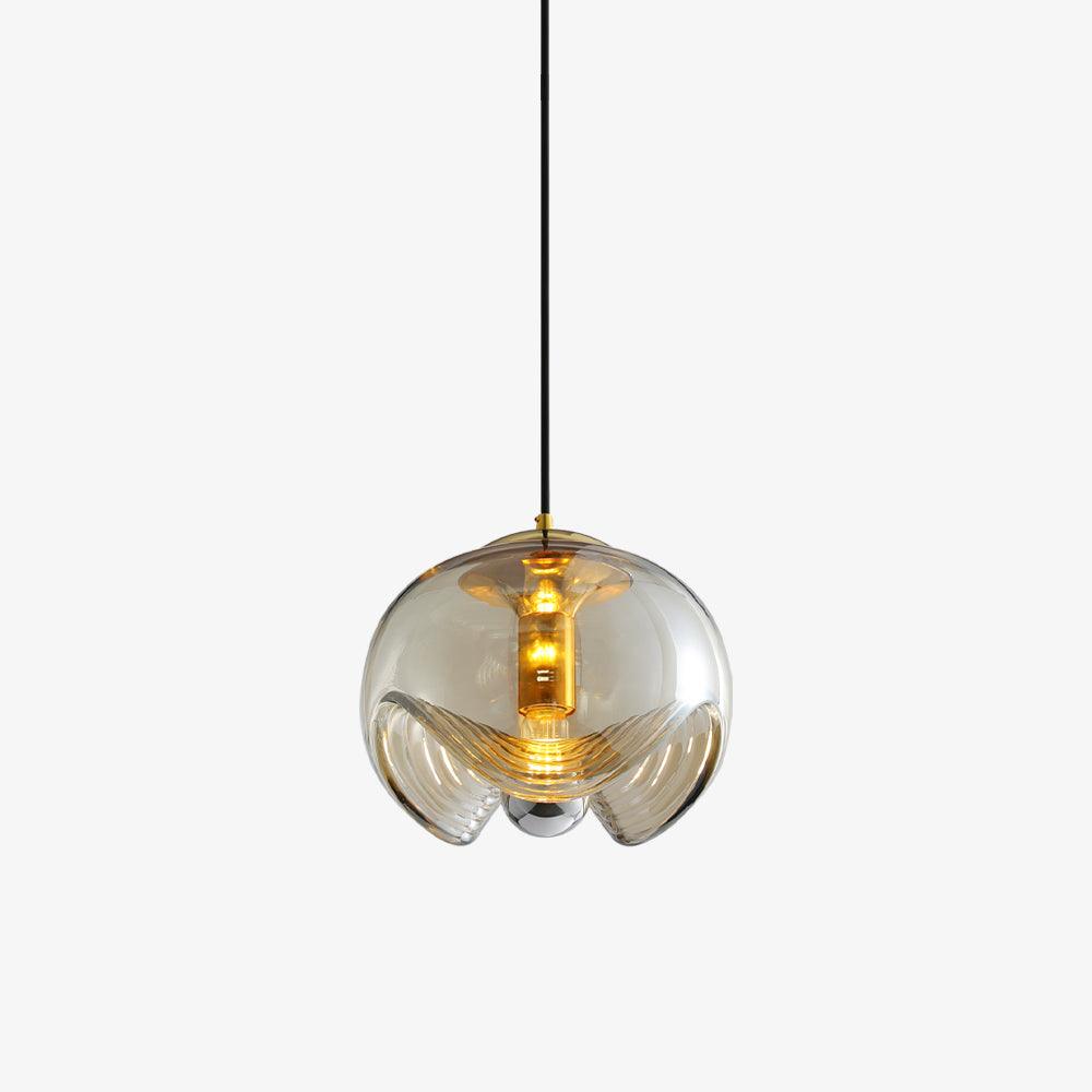 Product shot of this Clérachic pendant's amber glass shade and gold frame, lit warmly against a plain grey backdrop.