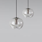 Two clear glass pendants with silver frames hang at different heights against a plain grey backdrop, this Clérachic fixture shown as a pair.