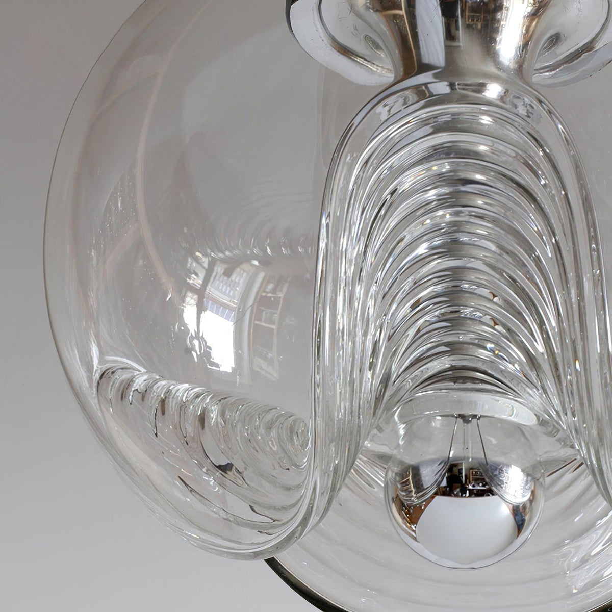 Close view of this Clérachic pendant's clear glass shade, its ribbed scalloped folds catching daylight around a chrome socket.